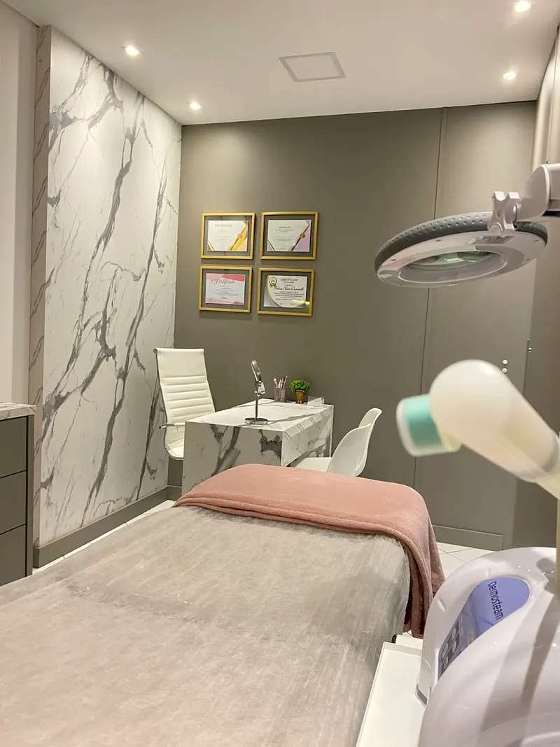Sala de atendimento com maca, lupa de luz e mesa